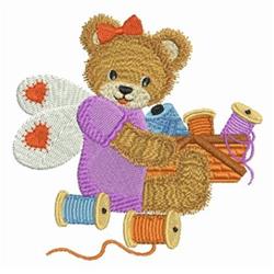Applique bear with butterfly wings, wearing a purple shirt and red bow, surrounded by colorful spools of thread.