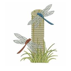 Applique of two dragonflies, one blue and one brown, resting on a textured post surrounded by lush grass.