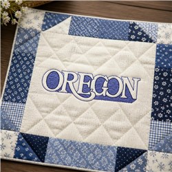 Oregon quilted design featuring bold blue text, surrounded by blue and white patchwork fabrics.