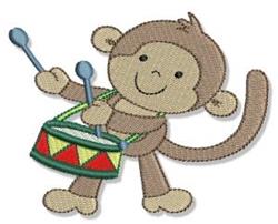 Playful monkey with light brown fur joyfully plays a colorful drum with red and green triangles.