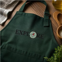 Green apron featuring 'EXPLORE' and a compass design, set in a cozy kitchen with wooden utensils.