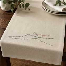 Cream table runner with 'let's get married!' text and leafy details, perfect for modern rustic wedding decor.