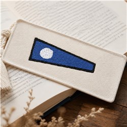 Modern bookmark with a blue triangle and white circle on beige fabric, featuring a minimalist design.