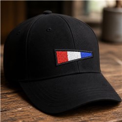 Black baseball cap with a vibrant red, white, and blue embroidered patch on a wooden surface.