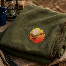 Embroidered eagle with a sunset gradient, set against an olive-green fleece blanket, creating an outdoor vibe.
