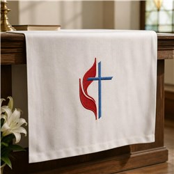 Cross with red flame and blue embroidery on white fabric table runner, perfect for church services.
