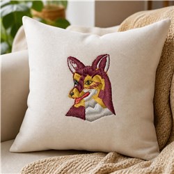 Embroidered fox head on a cozy pillow with vibrant orange and yellow details against neutral fabric.