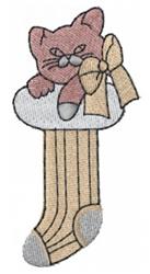 Playful kitten with pink and gray fur resting on a striped Christmas stocking, adorned with a light bow, perfect for festive
