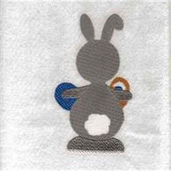 Playful gray rabbit with fluffy tail holding vibrant blue and orange Easter eggs on a soft white background.