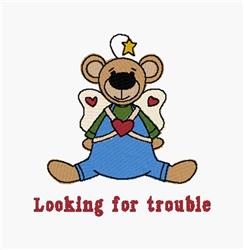 Playful bear with angelic wings in blue overalls and green shirt, surrounded by hearts, stitched text 'Looking for trouble'.