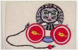 Playful gray cat face with green eyes above vibrant red yarn balls and a bell-decorated string, perfect for whimsical themes.