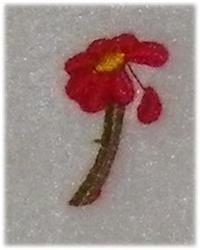 Applique red flower with vibrant petals, yellow center, and green stem on a light background.