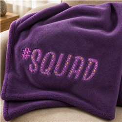 #SQUAD text design on a cozy purple blanket draped over a chair, featuring playful dots for a vibrant touch.