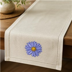 Daisy with purple petals and yellow center elegantly embroidered on a neutral table runner, enhancing home decor.