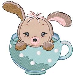 Cute bunny with fluffy ears peeking from a polka-dotted blue cup, perfect for whimsical embroidery.