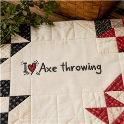 Playful 'I ❤️ Axe Throwing' text on quilted fabric with black and red geometric patterns, featuring plants.