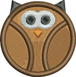Playful owl face applique design within a circular frame, featuring large eyes and an orange beak in warm brown tones.