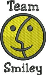 Playful smiley face in bright yellow with a black outline and 'Team Smiley' text below for cheerful machine embroidery.