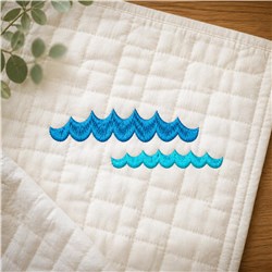 Stylized ocean waves in shades of blue on light quilted fabric create a modern coastal design.