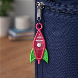 FSL rocket-shaped zipper pull in red and green on a navy blue bag, featuring a playful and colorful design.
