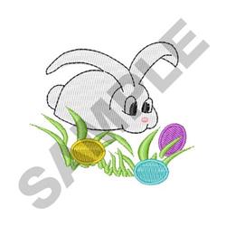 Playful rabbit with big eyes searches green grass for colorful Easter eggs in yellow, purple, and blue.