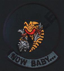 Stylized insect patch with vibrant orange and yellow robotic elements, featuring bold colors and 'NOW BABY...' phrase.