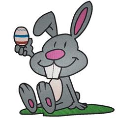 Playful gray rabbit holds a colorful Easter egg on green grass, perfect for festive decorations.