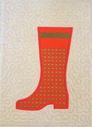 Vibrant red rubber boot with a green band, set against a soft beige quilted background for playful fall decor.