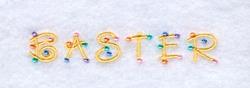 Colorful word art 'BASTER' in golden thread with beads, perfect for whimsical Easter celebrations.
