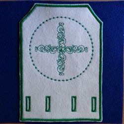 Embroidered patch featuring an elegant cross pattern outlined in green thread on white fabric.