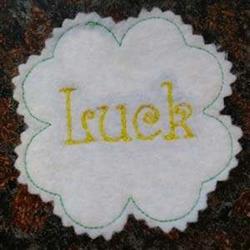 FSL embroidered patch displaying the word 'Luck' in yellow on scalloped white felt with green outline, festive design.