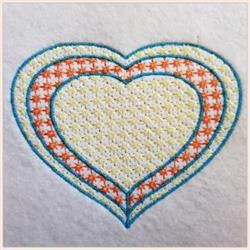 Colorful heart shape with layered patterns in blue, yellow, and orange, set on light fabric.