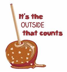 Candy apple with glossy caramel coating and wooden stick, featuring playful red text 'It's the OUTSIDE that counts' for fall.